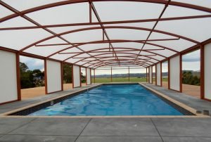 Free standing arched canopy covering a pool by Fresco Shades